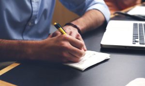 Man writing in notepad at his desk